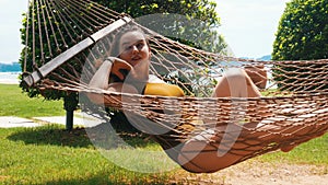 A young pretty woman in swimming suit lying in the hammock and enjoy her holidays