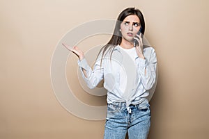 Young pretty woman talk phoneisolated on beige background