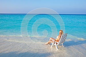 Young pretty woman tans in beach chair