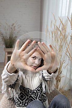 young pretty woman, teenager girl makes a frame gesture with her palms in front of her face