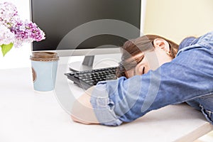 Young pretty woman tired and exhausted of work lying on table in front of computer and taking a break