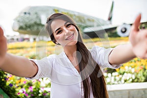 Young pretty woman tourist take selfie with frowers airplane in miracle garden