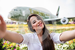 Young pretty woman tourist take selfie with frowers airplane in miracle garden