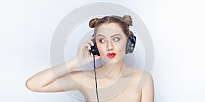 Young pretty woman trendy makeup bright red lips bun hairstyle bare shoulders act the ape with big dj headphones on white studio b