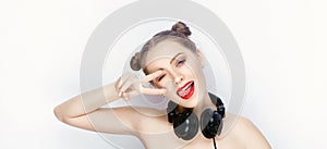 Young pretty woman trendy makeup bright red lips bun hairstyle bare shoulders act the ape with big dj headphones on white studio b