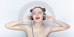 Young pretty woman trendy makeup bright red lips bun hairstyle bare shoulders act the ape with big dj headphones on white studio b
