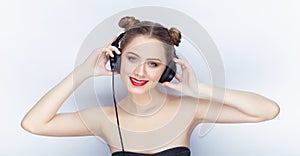 Young pretty woman trendy makeup bright red lips bun hairstyle bare shoulders act the ape with big dj headphones on white studio b