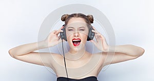 Young pretty woman trendy makeup bright red lips bun hairstyle bare shoulders act the ape with big dj headphones on white studio b