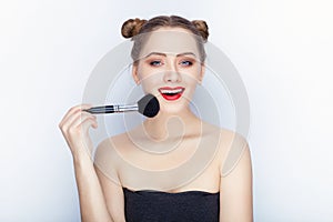 Young pretty woman trendy makeup bright red lips bun hairstyle bare shoulders act the ape with brush white studio background