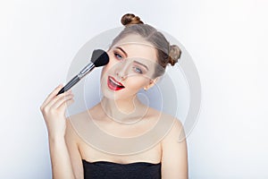 Young pretty woman trendy makeup bright red lips bun hairstyle bare shoulders act the ape with brush white studio background