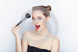 Young pretty woman trendy makeup bright red lips bun hairstyle bare shoulders act the ape with brush white studio background