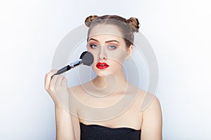 Young pretty woman trendy makeup bright red lips bun hairstyle bare shoulders act the ape with brush white studio background