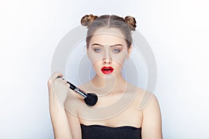 Young pretty woman trendy makeup bright red lips bun hairstyle bare shoulders act the ape with brush white studio background