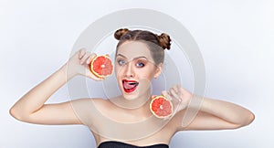 Young pretty woman trendy makeup bright red lips bun hairstyle bare shoulders act the ape with grapefruits white studio background