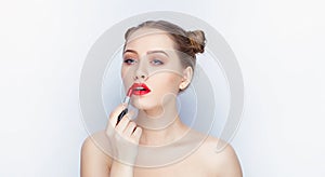 Young pretty woman trendy makeup bright red lips bun hairstyle bare shoulders act the ape with lipstick white studio background