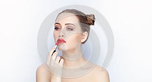 Young pretty woman trendy makeup bright red lips bun hairstyle bare shoulders act the ape with lipstick white studio background