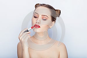 Young pretty woman trendy makeup bright red lips bun hairstyle bare shoulders act the ape with lipstick white studio background