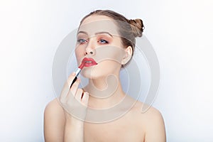 Young pretty woman trendy makeup bright red lips bun hairstyle bare shoulders act the ape with lipstick white studio background