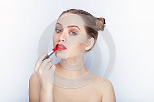 Young pretty woman trendy makeup bright red lips bun hairstyle bare shoulders act the ape with lipstick white studio background