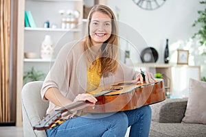 young pretty woman tuning guitar