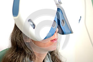 Young pretty woman undergone lens fitting procedure with automated ophthalmological equipment photo