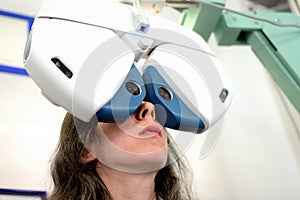 Young pretty woman undergone lens fitting procedure with automated ophthalmological equipment photo