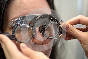 Young pretty woman undergone lens fitting procedure in vintage style lens testing matching frame with ophthalmologist optometrist