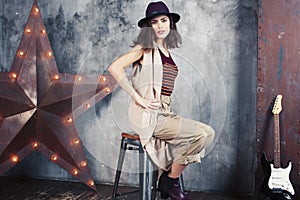 Young pretty woman waiting alone in modern loft studio, fashion clothers wearing hat, lifestyle and people home concept