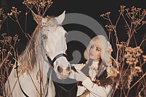 Young pretty woman walking with horse outdoors