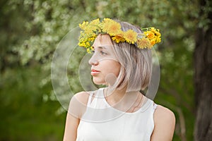 Young pretty woman wearing flowers wreath in spring park outdoor