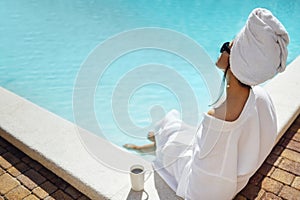 Young pretty woman in a white bathrobe holds a cup of coffee