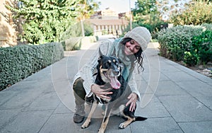 Young and pretty woman in a white cap hugs and kisses her dog with one eye of each color. Love between owner and dog