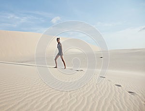 Young pretty woman in white sand dunes like a goddes of darkness