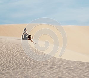 Young pretty woman in white sand dunes like a goddes of darkness