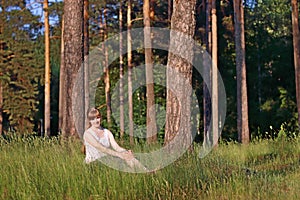 Young pretty woman in white smiles and sits in green grass