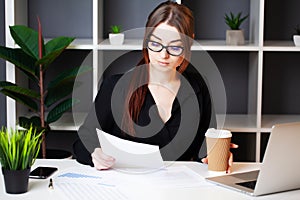 Young pretty woman working at the computer in the office and filling documents