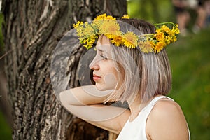 Young pretty woman in yellow flowers wreath outdoor. Healthy girl in flowers garden