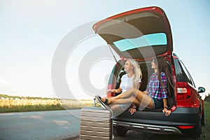 Young pretty women friends travel by car. Summer holidays and active recreation. Positive emotions from the adventure