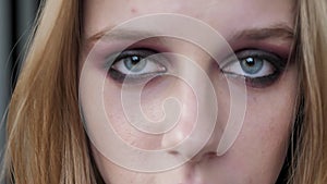 Young pretty women with heavy make up looking into camera and closing eyes, portrait, striped wall background