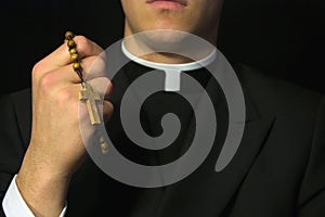 Young Priest praying with rosary