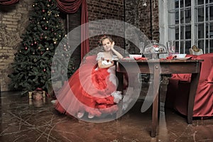 Young princess in a red and white dress sitting