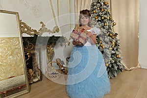 Young Princess in white with a blue elegant dress with a gift in