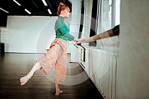 Young professional ballet dancer with hair bun doing pas