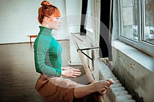 Young professional ballet dancer with hair bun standing with a straight back.