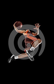 Young professional basketball player in action, motion isolated on black background, look from the bottom. Concept of