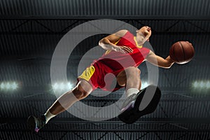 Young professional basketball player in action, motion isolated on black background, look from the bottom. Concept of