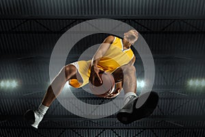 Young professional basketball player in action, motion isolated on black background, look from the bottom. Concept of
