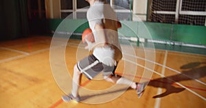 Young professional basketball player plays throws the ball into the basket night darkness silhouette rear view dribbling