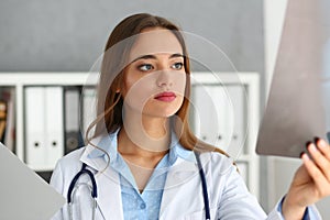 Young professional beautiful female doctor examining x-ray of patient