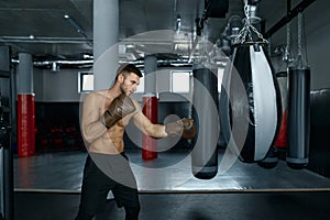 Young professional boxer training with punching bag